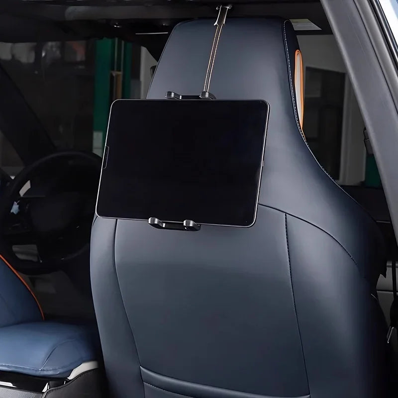 Black tablet mounted on a blue leather car headrest using a secure strap holder.