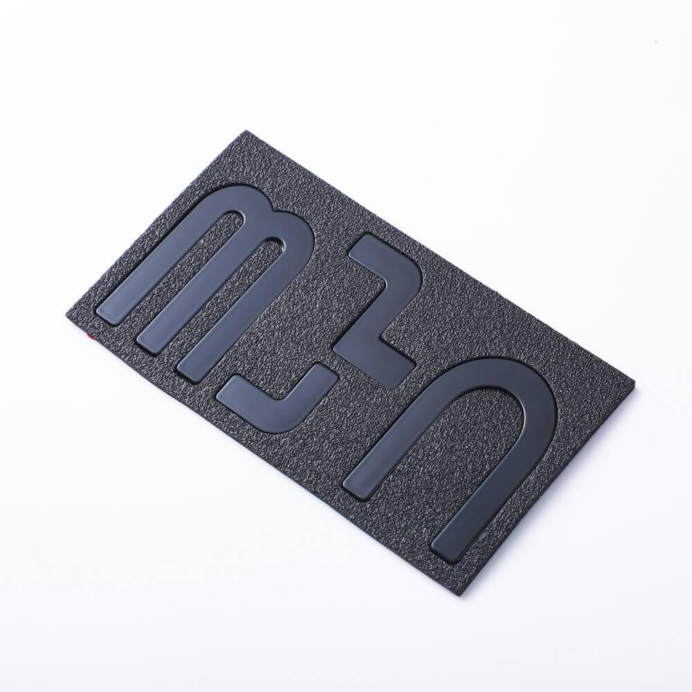Black textured BYD emblem with matte grey letters on a rectangular base.
