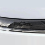 Close-up of a black carbon fiber textured car accessory with a glossy finish.