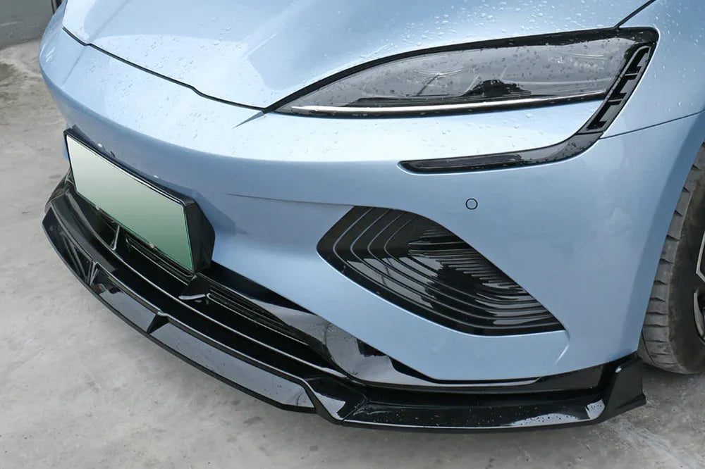Glossy black aerodynamic front lip spoiler installed on a light blue BYD car bumper.