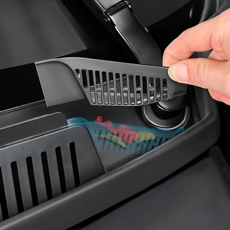 Hand lifting a black plastic slotted organizer tray from a car console compartment.