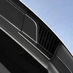 Close-up of a black matte plastic car vent accessory on a light blue vehicle.