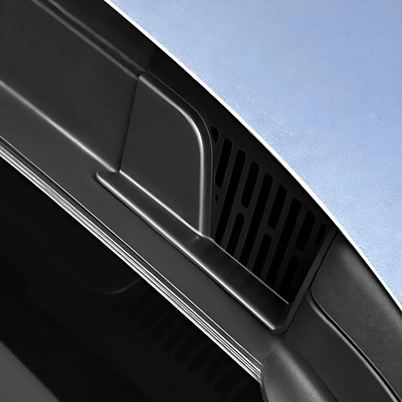 Close-up of a black matte plastic car vent accessory on a light blue vehicle.