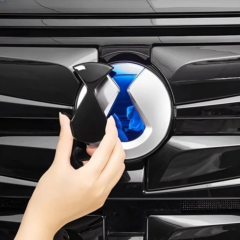 Black and blue metallic emblem cover for BYD car grille, featuring a sleek dual-tone finish.