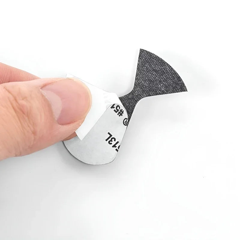 Close-up of a hand peeling the white backing from a black textured adhesive pad.