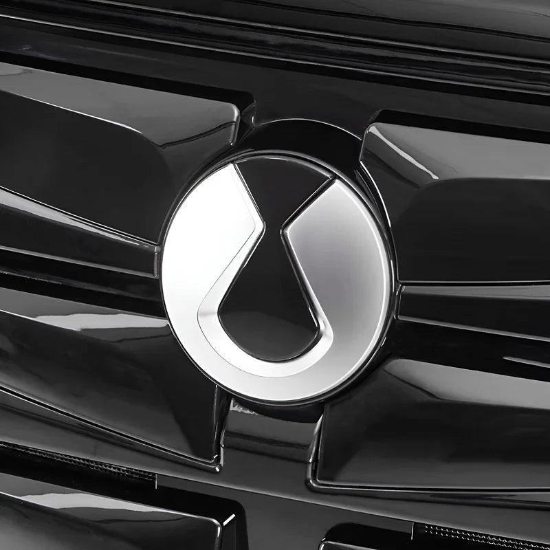 Close-up of a silver chrome car emblem on a glossy black vehicle grille.