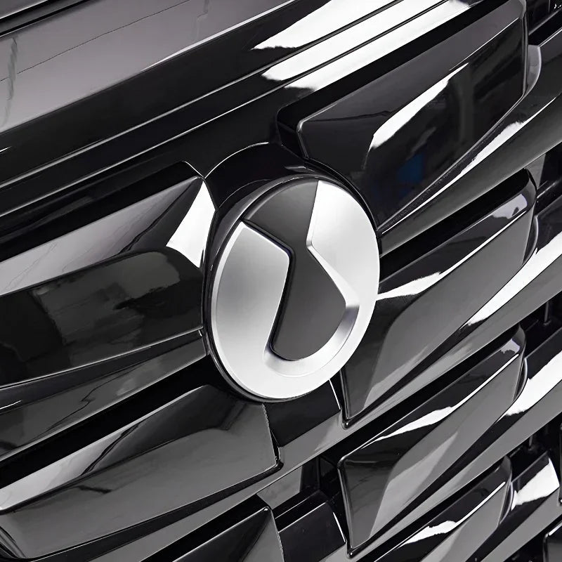 Close-up of a glossy black car grille featuring a sleek silver and black emblem.