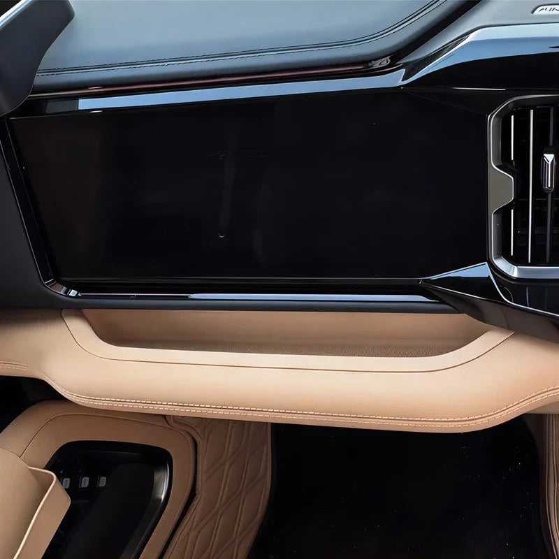 Black glossy dashboard screen with beige leather trim and stitched interior details.