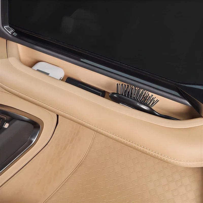 Tan leather dashboard storage compartment featuring a black cleaning brush and white accessory.