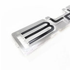 Close-up of a transparent acrylic car emblem with black inset lettering.