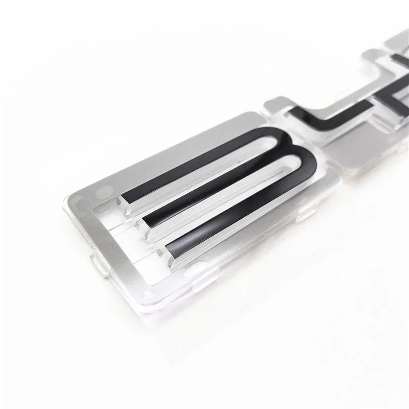 Close-up of a transparent acrylic car emblem with black inset lettering.