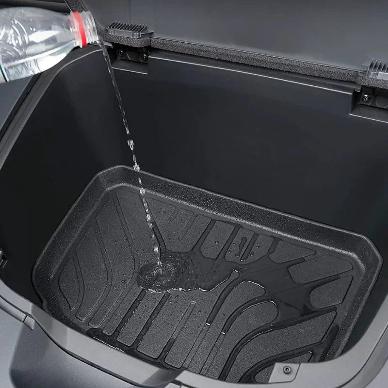 Water being poured onto a black waterproof TPE trunk mat for easy cleaning.