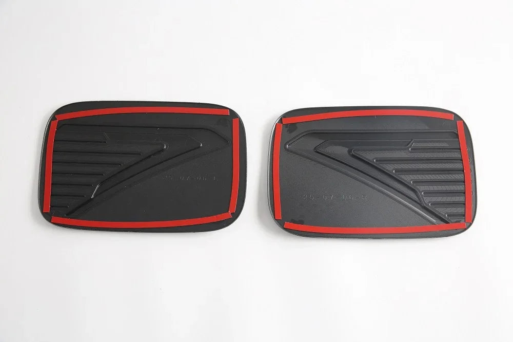 Pair of black textured car pedal covers with distinctive red trim accents.