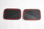 Pair of black textured car pedal covers with distinctive red trim accents.