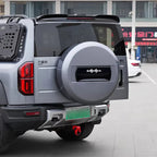 Silver rugged rear spare tire cover with black accent detail on a grey SUV.