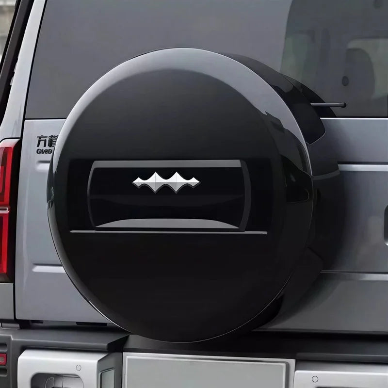 Glossy black hard-shell spare tire cover with a sleek silver emblem on a grey SUV.
