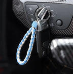 Black car key fob with a blue and white braided leather keychain loop.