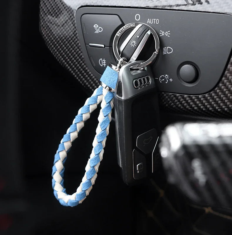 Black car key fob with a blue and white braided leather keychain loop.
