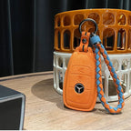 Orange suede car key fob cover with a blue and orange braided fabric wrist strap.