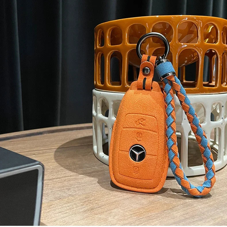 Orange suede car key fob cover with a blue and orange braided fabric wrist strap.