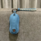 Light blue suede car key fob cover with a matching braided blue and white leather strap.