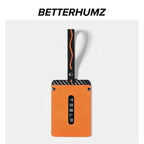 Orange leather car key fob with black carbon fiber trim and decorative stitching.