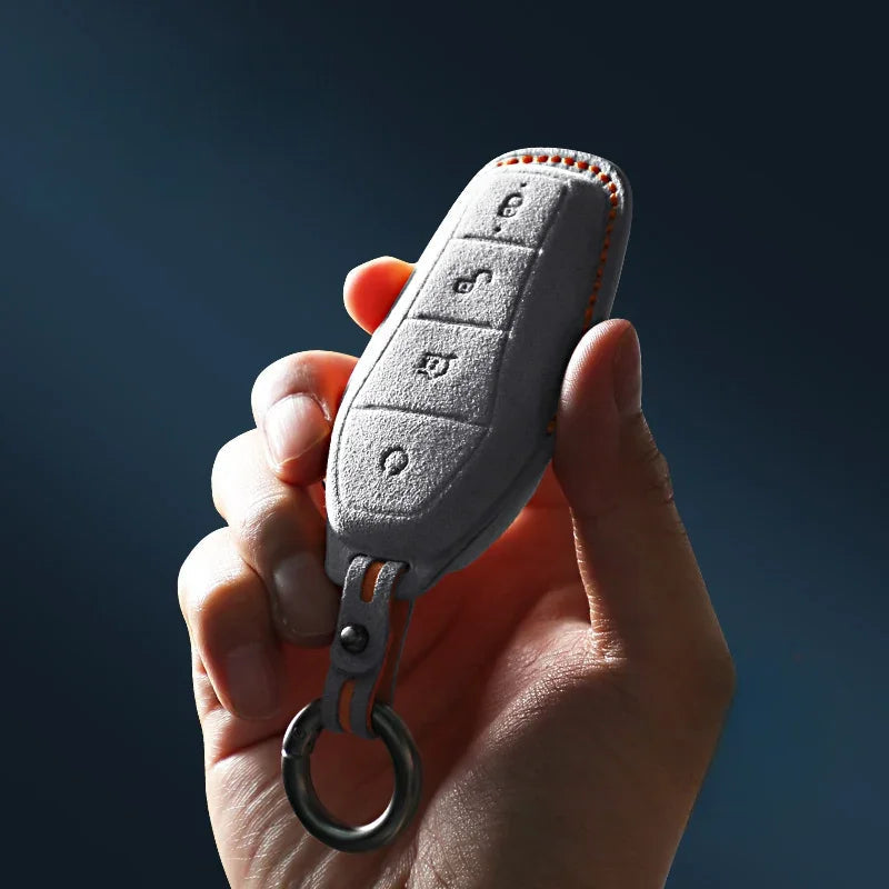 Grey textured leather car key fob cover with orange contrast stitching and metal ring.