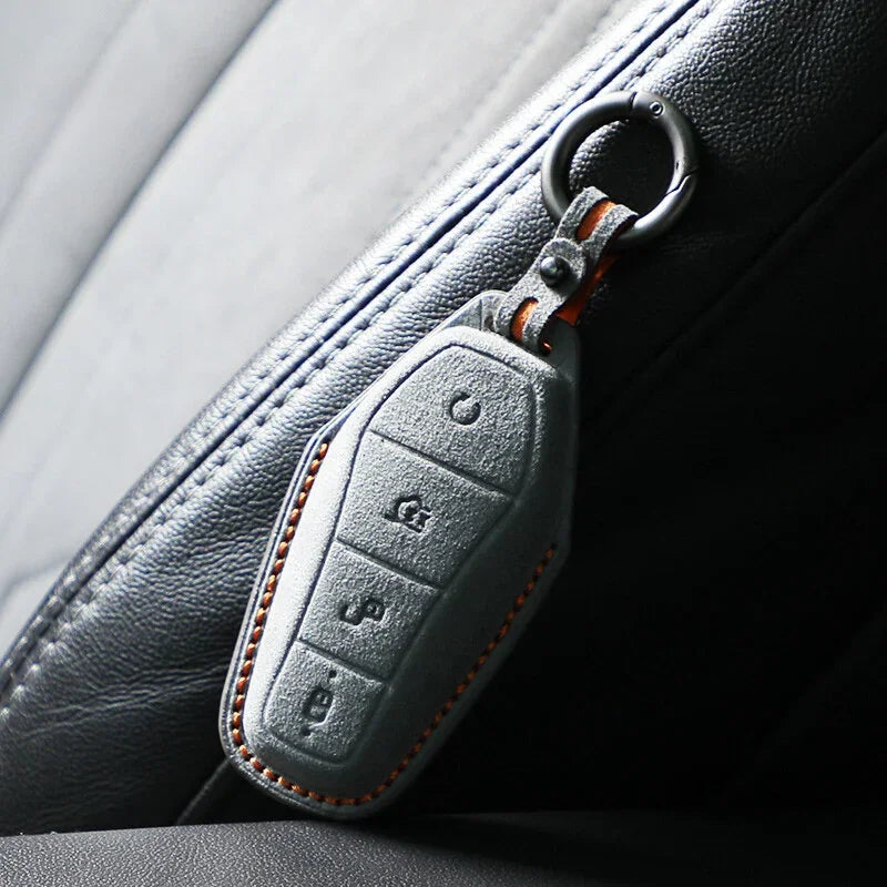 Black leather car key cover with orange stitching attached to a zipper