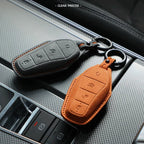 Two suede leather car key covers in black and orange with precise stitching and keyrings.