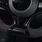 Black carbon fiber steering wheel trim with red stitching and premium suede texture.