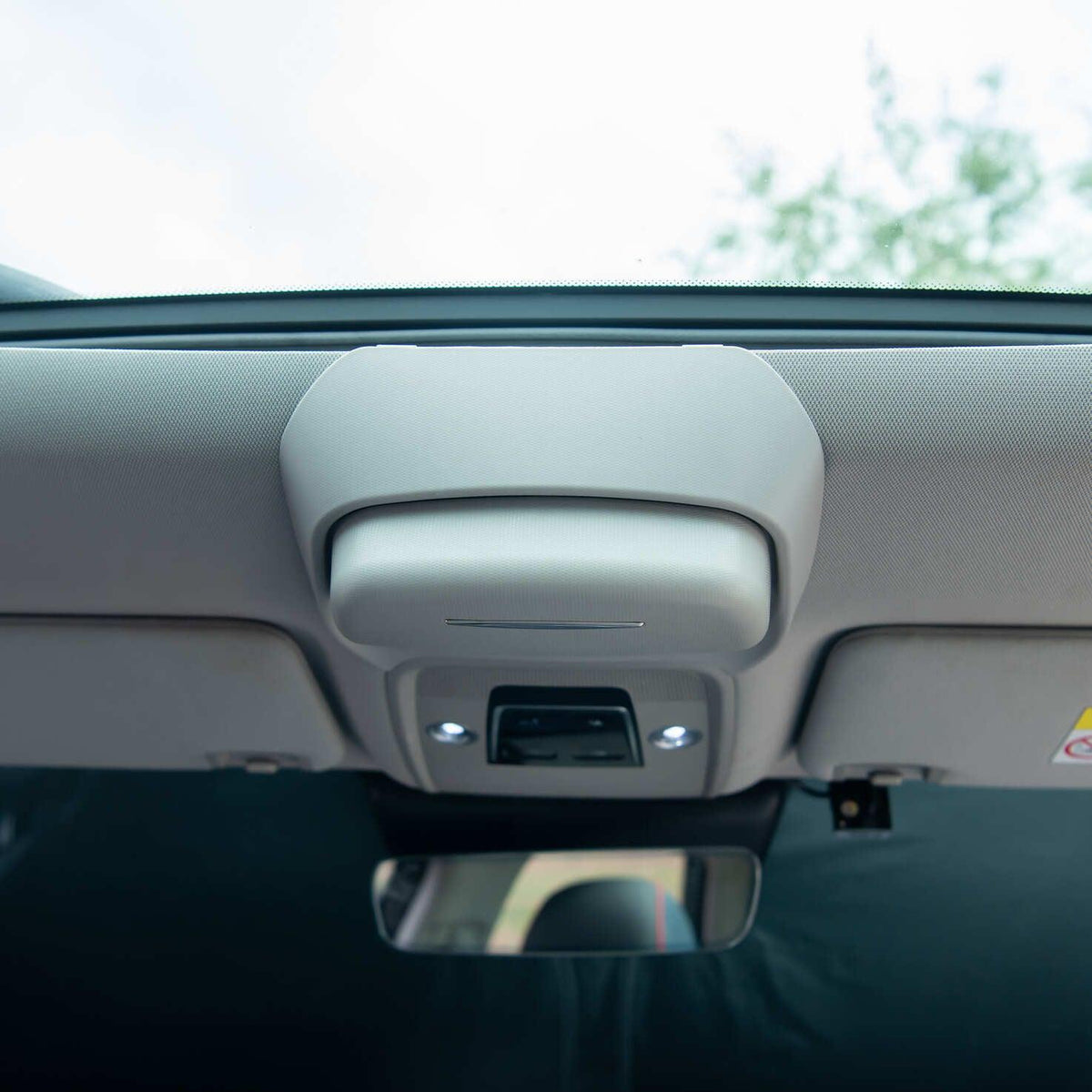Grey interior overhead console with integrated light and control buttons in a car ceiling.