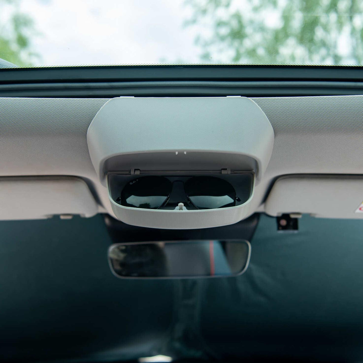 Grey overhead car console featuring a built-in sunglasses storage compartment.