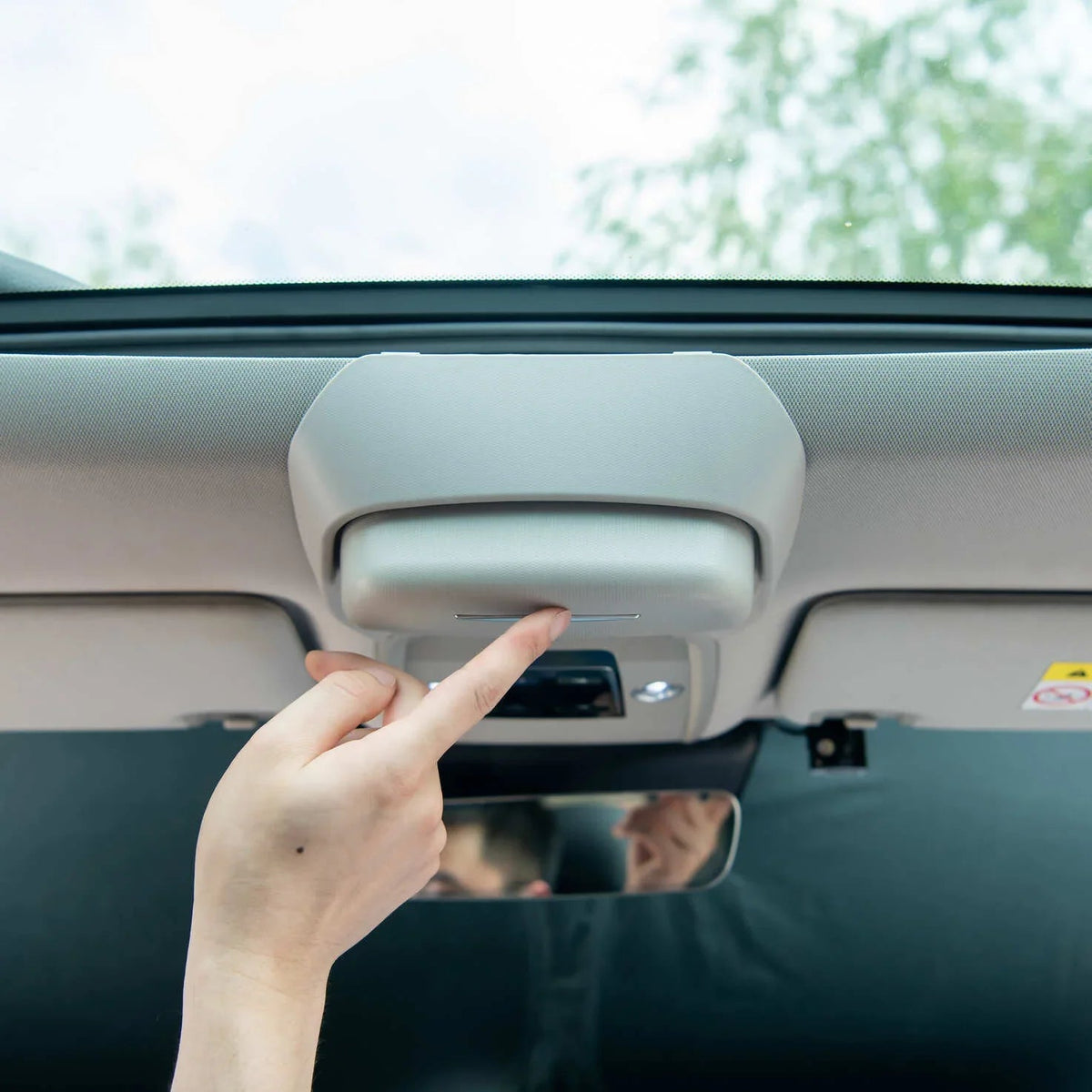 Person pressing the button on a grey interior car overhead console light.