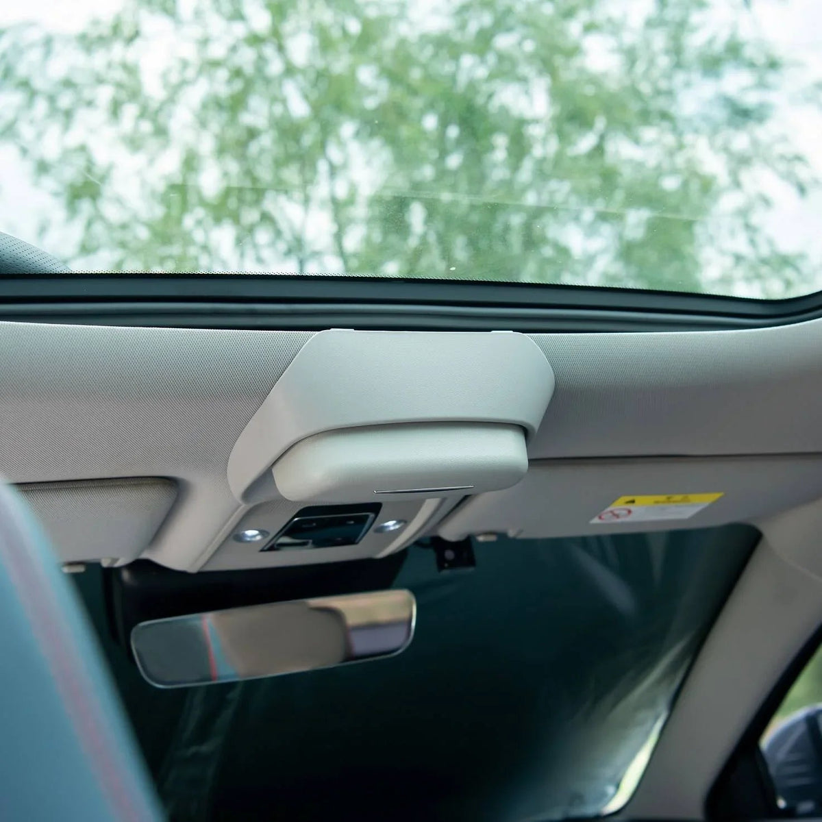 Light gray interior car ceiling featuring a sleek sun visor and rearview mirror.