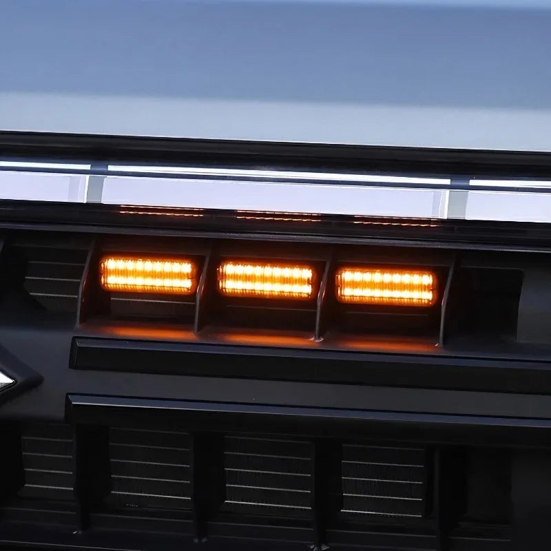 Close-up of three amber LED marker lights integrated into a black matte car grill.