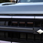 Close-up of a grey car grill featuring a sleek chrome trim and black matte accents.