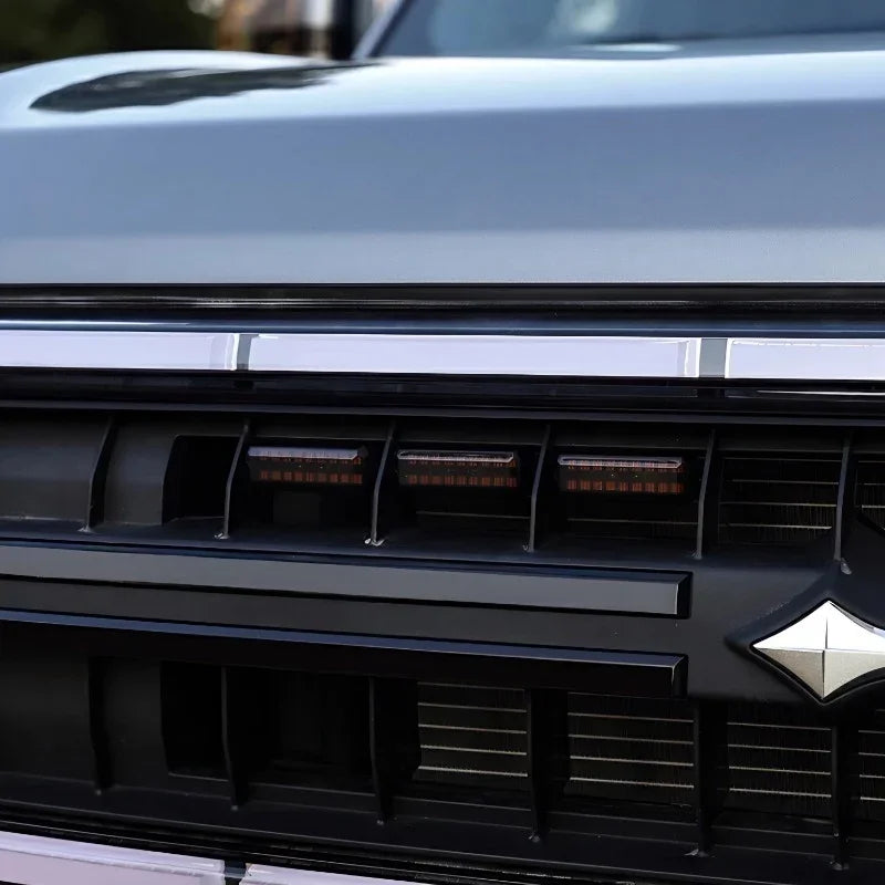 Close-up of a grey car grill featuring a sleek chrome trim and black matte accents.