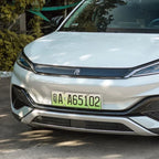 Close-up of a white BYD electric vehicle front bumper featuring a sleek black trim and license plate.