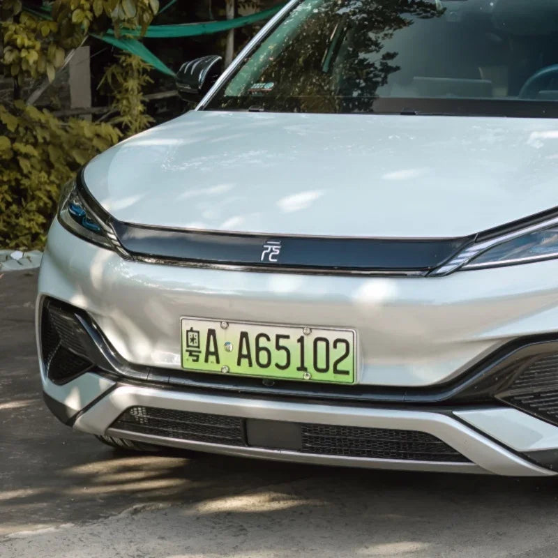 Close-up of a white BYD electric vehicle front bumper featuring a sleek black trim and license plate.