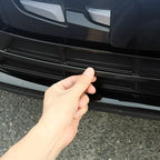 Black high-gloss protective trim piece being installed on a vehicle bumper.