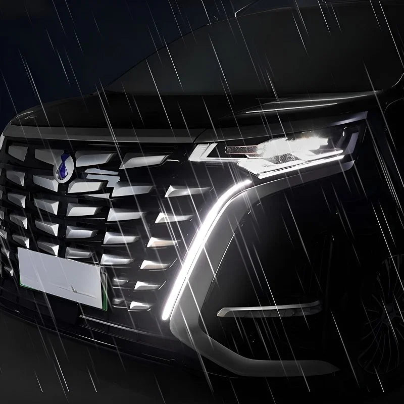 Close-up of a black car's sleek LED headlights and chrome grille shining in the rain.