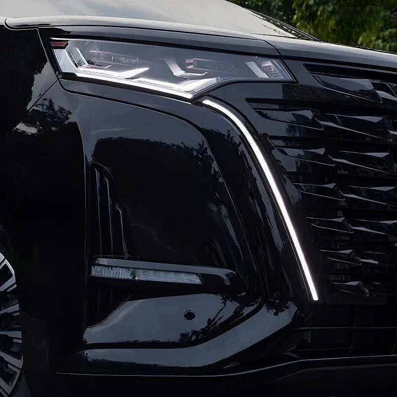 Close-up of a sleek black car headlight and front grille design.