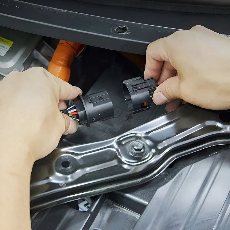 Hands connecting black plastic electrical wiring connectors in a car engine bay