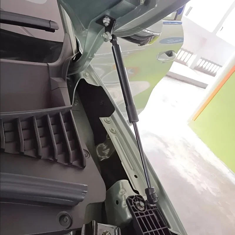 Close-up view of a black hydraulic gas strut supporting an open car hood.