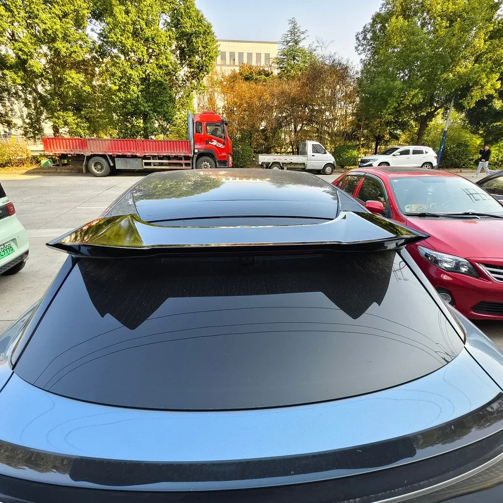 Glossy black aerodynamic rear spoiler installed on a car's rear window for enhanced style.