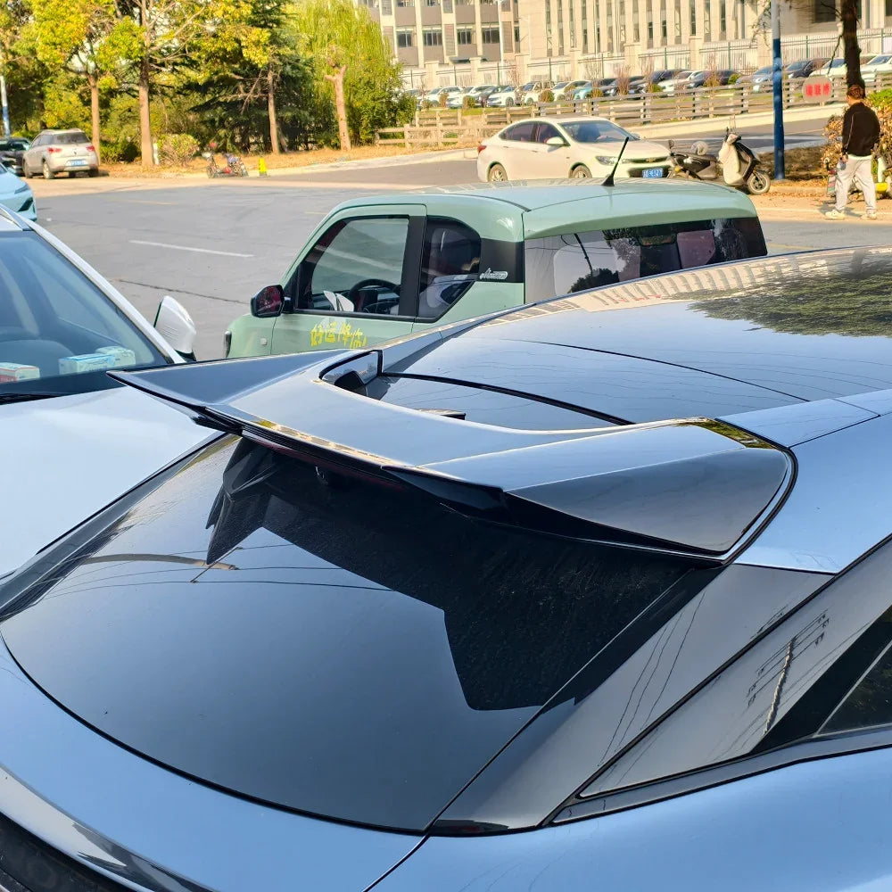 Sleek black aerodynamic rear spoiler installed on a grey car trunk for enhanced styling.