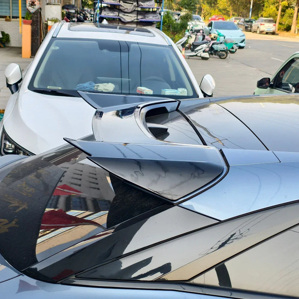 Glossy black shark fin antenna on a sleek dark car roof, featuring a polished aerodynamic design.
