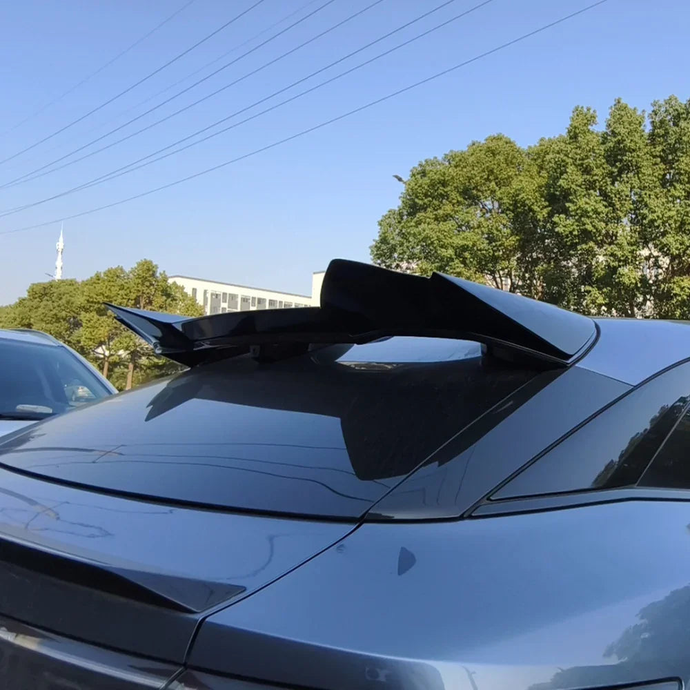 Glossy black aerodynamic rear spoiler installed on a dark grey BYD car roof.