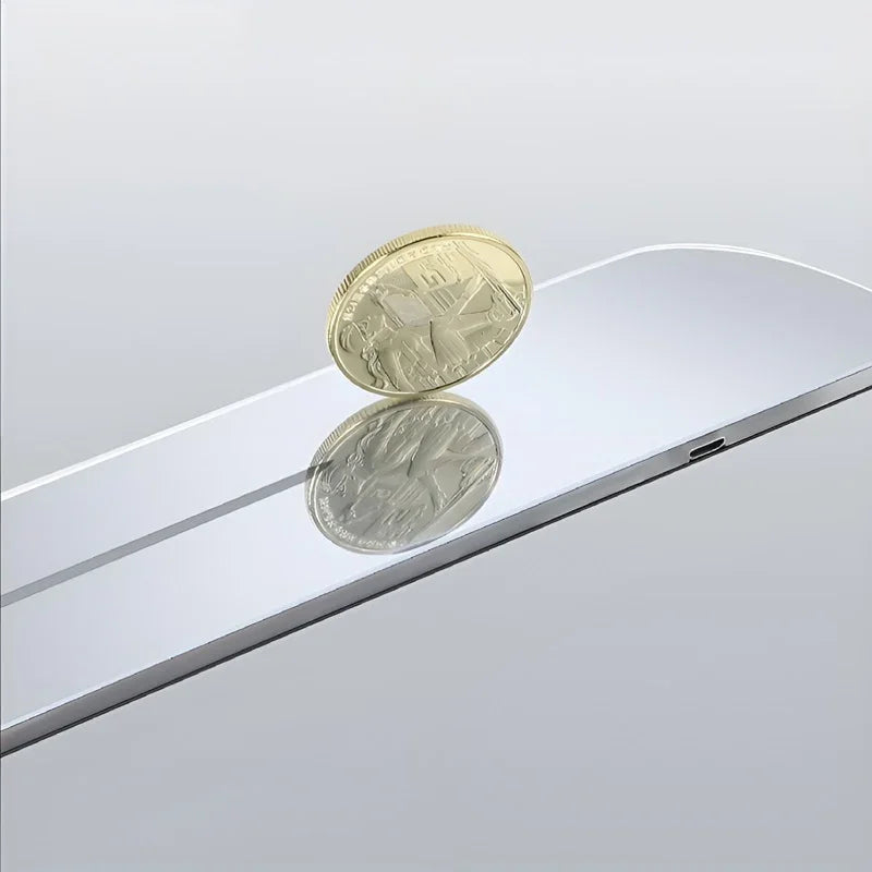 Gold coin balanced on a sleek, silver reflective surface showcasing a mirrored finish.