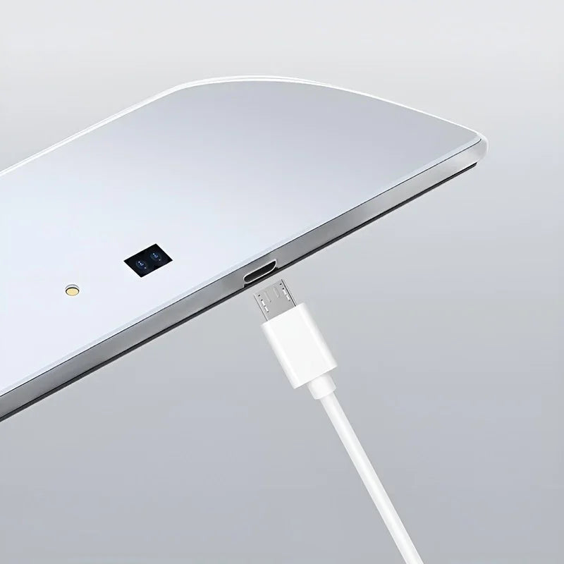 Close-up of a white USB cable plugging into a sleek silver metallic electronic device.